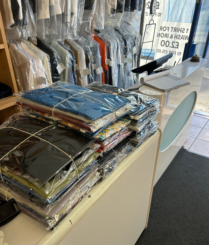 Stack of folded clothes wrapped in plastic on a counter in a store.